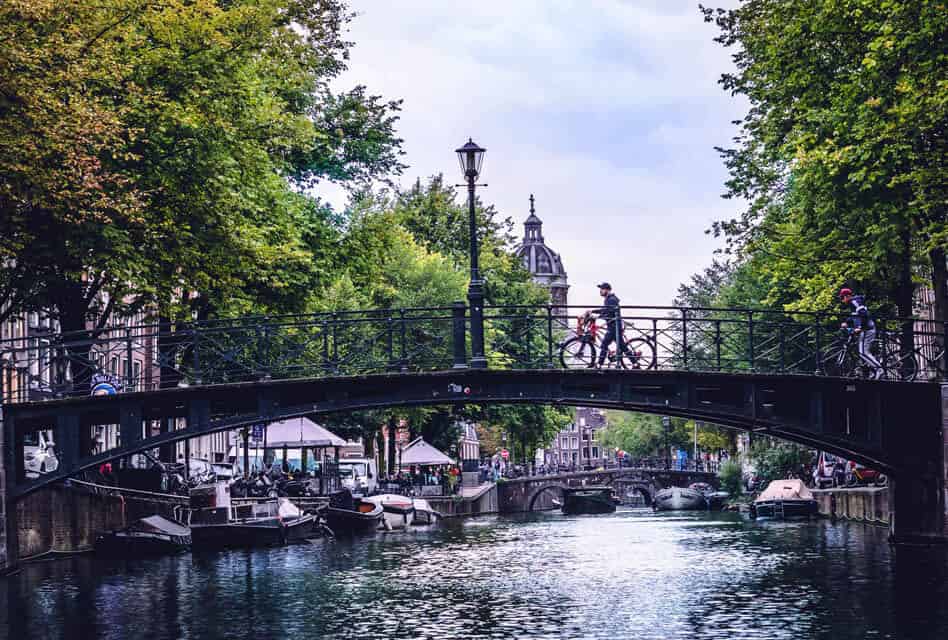 cycling over canal bridge amsterdam